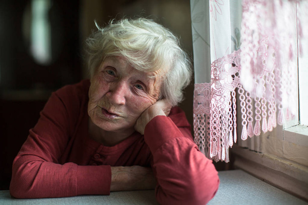 Емоції літньої жінки, що сидить за столом. 90-річний
. - Фото, зображення