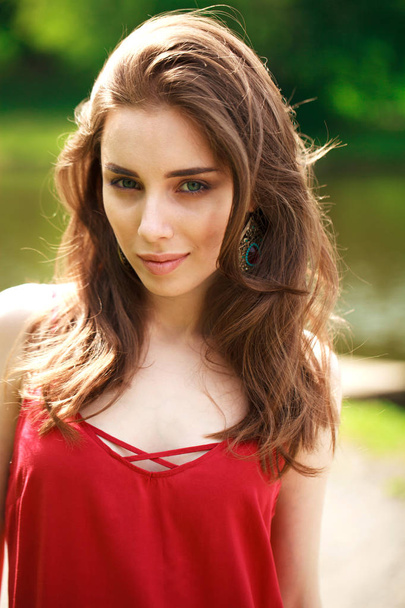Portrait close up of young beautiful happy woman in red dress, summer outdoors - 写真・画像