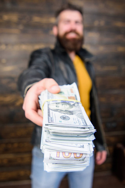 Richness and wellbeing. Mafia business. Man brutal bearded hipster wear leather jacket and hold cash money. Illegal profit and black cash. Guy mafia dealer with cash profit. Man give cash money bribe - Photo, image
