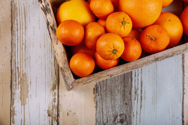 Fresh tangerines in old box with on wooden background. Top view - Photo, Image