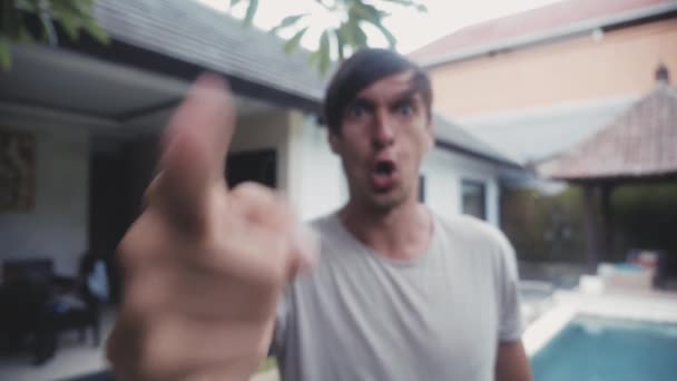 Wütender Mann droht mit dem Finger und spricht aggressiv schreiend auf den Hinterhof des Hauses in seinem Hof. Gewaltandrohung - Filmmaterial, Video