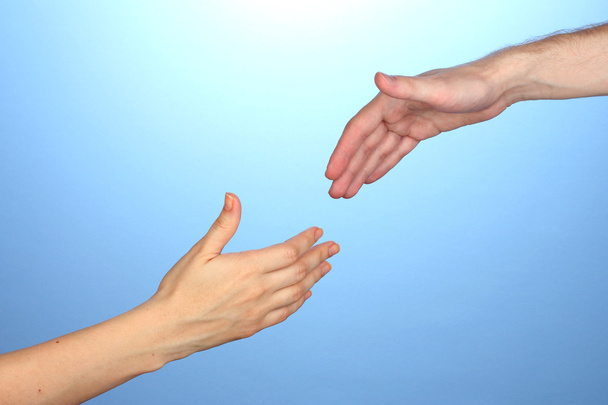 Women's hand goes to the man's hand on blue background - Foto, imagen