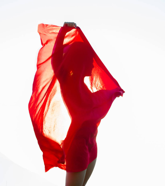 woman wrapped in a red scarf in the wind - Фото, изображение