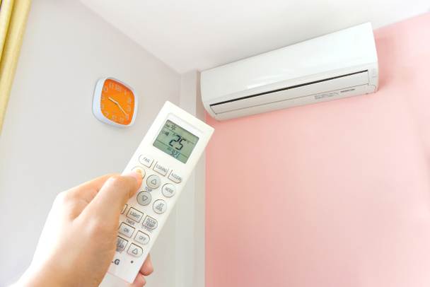 Mão ligando o sistema de ar condicionado em casa a 25 graus, economia de energia
 - Foto, Imagem
