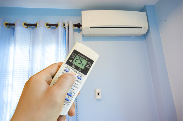 Hand draaien op home airconditioningsysteem bij 25 graden, energiebesparing - Foto, afbeelding