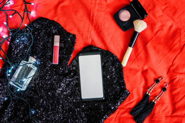 Mobile phone with blank screen on cocktail dress and near cosmetics and make up equipment. - 写真・画像