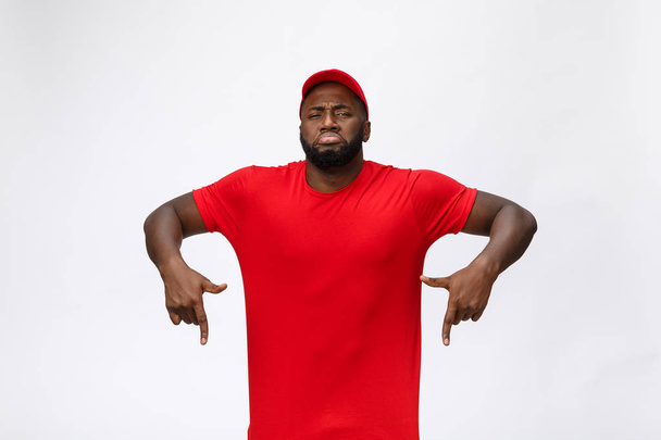 Portrait of handsome african american delivery man annoying pointing finger on side. Isolated over grey background. - Photo, image