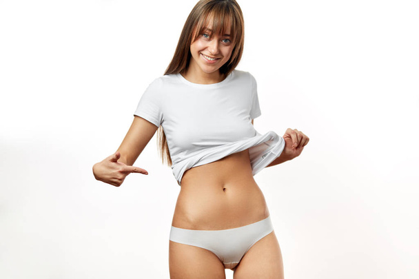 Beautiful woman in underwear testing fat layer on waist. - 写真・画像