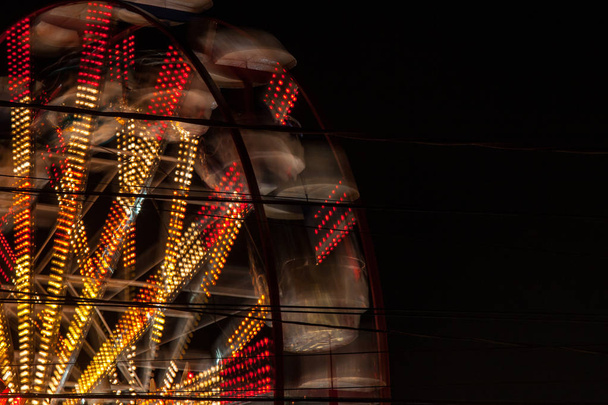 Forgó Ferris Wheel egy vidámparkban sárga és piros fények éjszaka háttér tapéta. Nem az emberek. - Fotó, kép