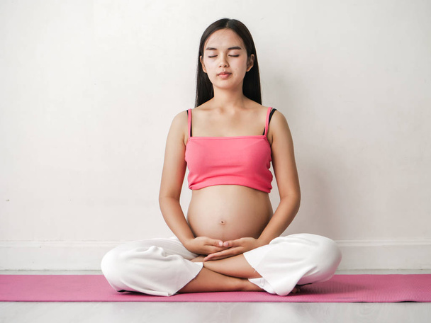 Aziatische zwangere vrouw doen mediteren thuis, lifestyle concept. - Foto, afbeelding