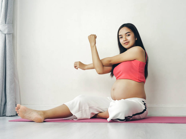 Asian pregnant woman doing yoga at home, lifestyle concept. - Фото, зображення