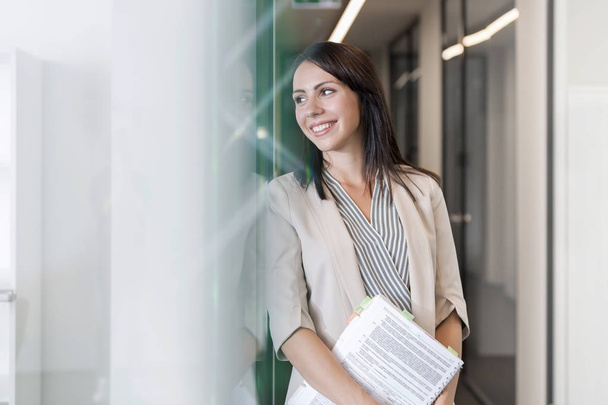 Smiling thoughtful businesswoman with documents at office - Foto, Imagen