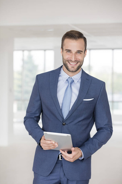 Portrait of handsome young businessman standing with digital tablet in new office - Fotoğraf, Görsel