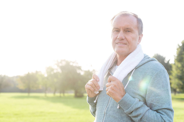 Portrait of fit athlete with towel in park on sunny day - Fotoğraf, Görsel
