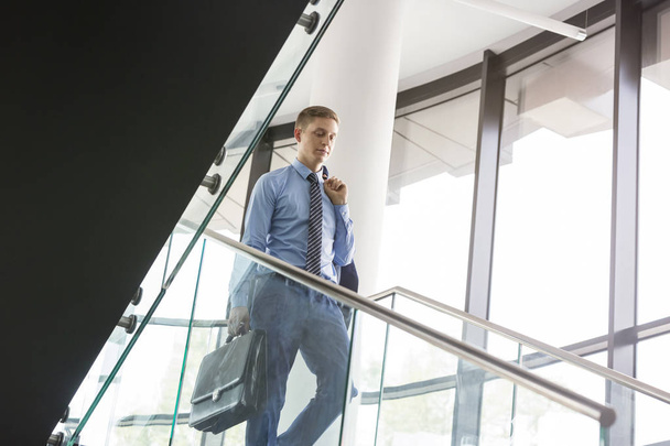 Low angle view of businessman moving down on staircase at office - Foto, imagen