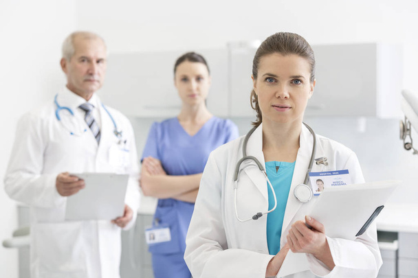 Portrait of confident doctors with medical reports standing at clinic - Фото, зображення