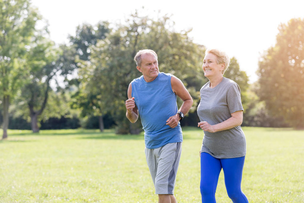 Healthy senior couple jogging in park - Foto, imagen