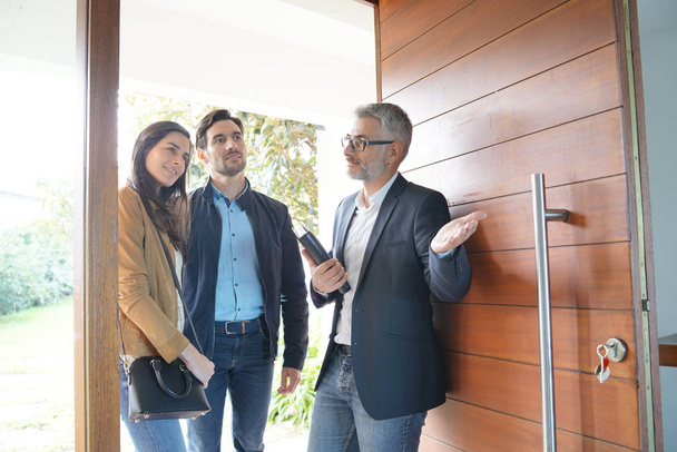 Couple with real-estate agent visiting modern house                               - Photo, image