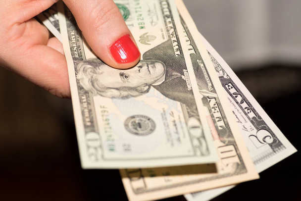 Een vrouw houdt dollarbiljetten in haar hand - Foto, afbeelding