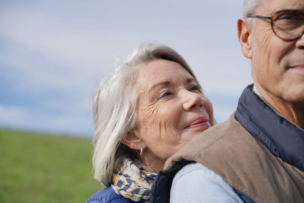Portrait of senior woman embracing her husband outdoors                                - Фото, зображення