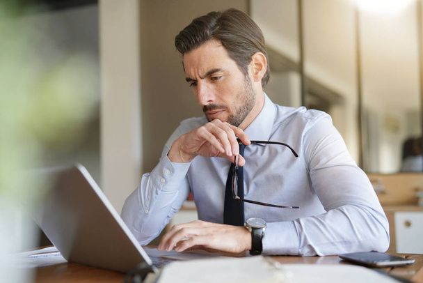 Attractive businessman concentrating on laptop in office - Photo, Image