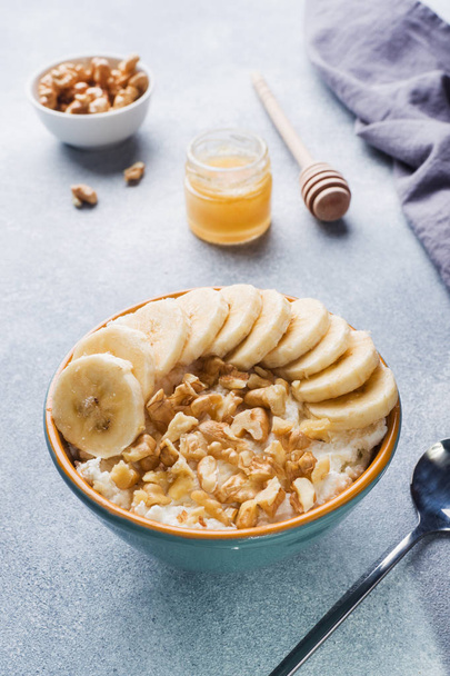 Healthy breakfast. Cottage cheese with banana and walnuts on grey background - Foto, afbeelding