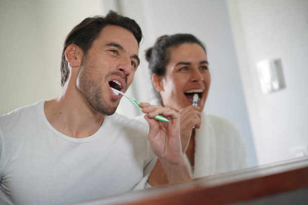  Fun attractive couple brushing teeth together                               - Foto, Imagem