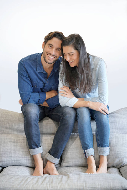 Isolated gorgeous smiling couple in denim on comfy couch - Fotó, kép