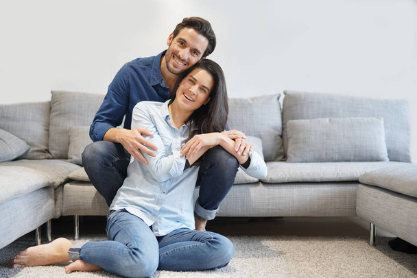 Isolated gorgeous smiling couple in denim on comfy couch - Foto, afbeelding