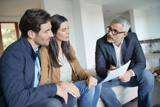    Couple with real-estate agent looking at contract in modern house                                                                                           - Foto, Bild