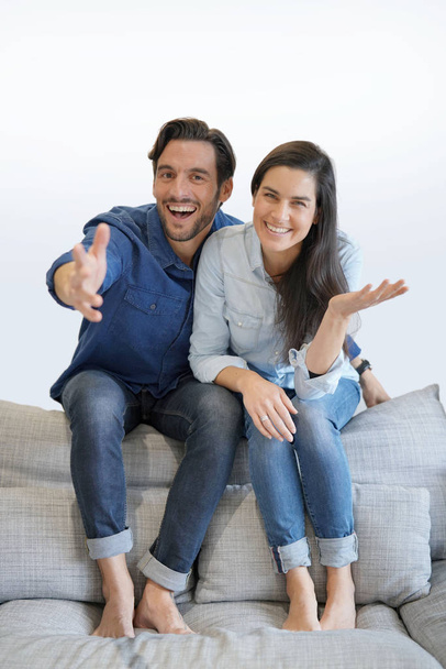 Isolated gorgeous smiling couple in denim on comfy couch - Φωτογραφία, εικόνα