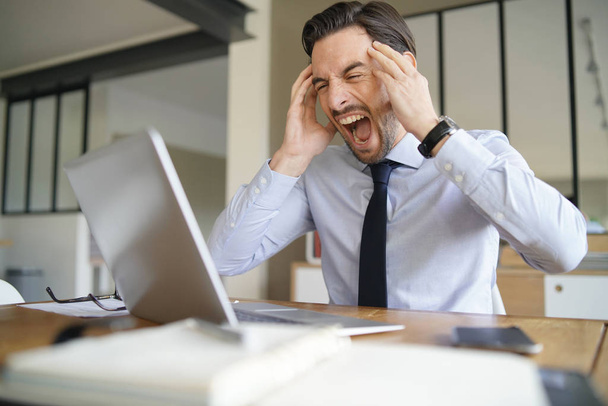 Angry businessman losing patience and screaming at laptop in modern office - Foto, immagini