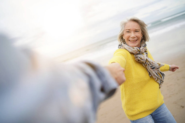 Energetic senior woman holding hands with husband in playful manner                                 - Foto, Bild