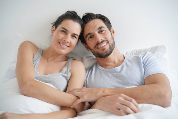Isolated stunning couple looking at camera smiling in bed - Fotó, kép