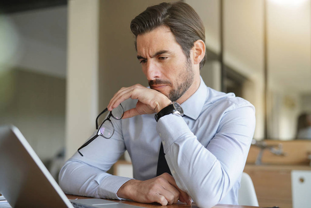 Attractive businessman concentrating on laptop in office - Foto, imagen