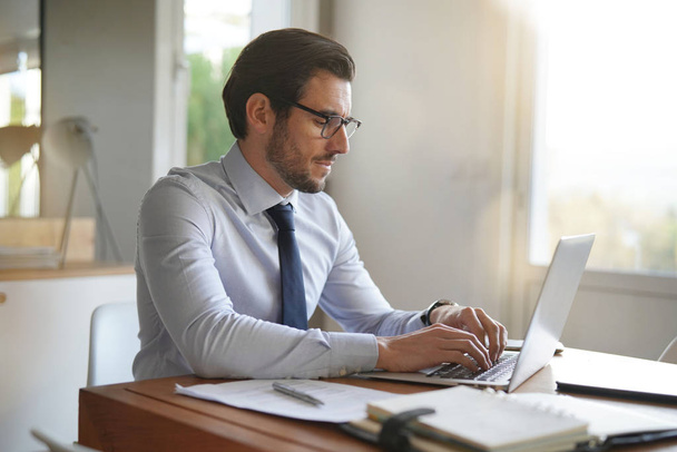 Attractive businessman typing on laptop in modern office - Fotografie, Obrázek
