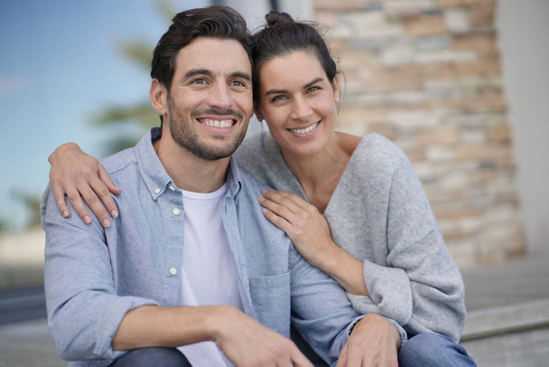  Portrait of very attractive couple smiling outside modern house                               - Фото, изображение