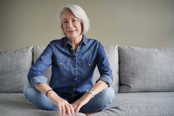 Modern senior woman in all denim on couch                               - Photo, image