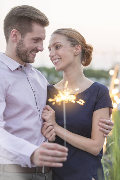 Smiling young businessman and businesswoman holding sparkler - Foto, Bild
