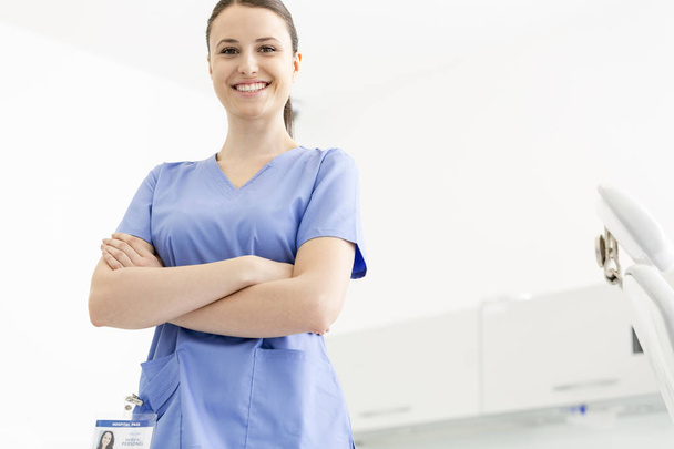 Portrait of confident smiling nurse with arms crossed at clinic - Photo, image