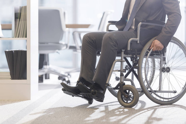 Low angle view of disabled businessman on wheelchair at modern office - Photo, Image