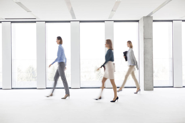 Defocused image of businesswomen walking in empty workspace - Zdjęcie, obraz