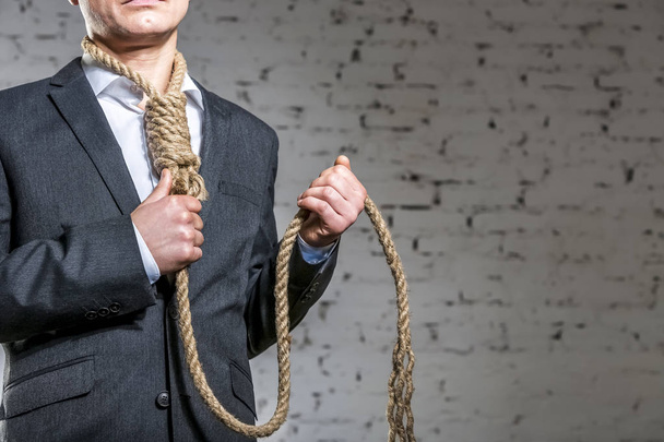 Midsection of businessman with rope noose standing against brick wall at office - Fotografie, Obrázek