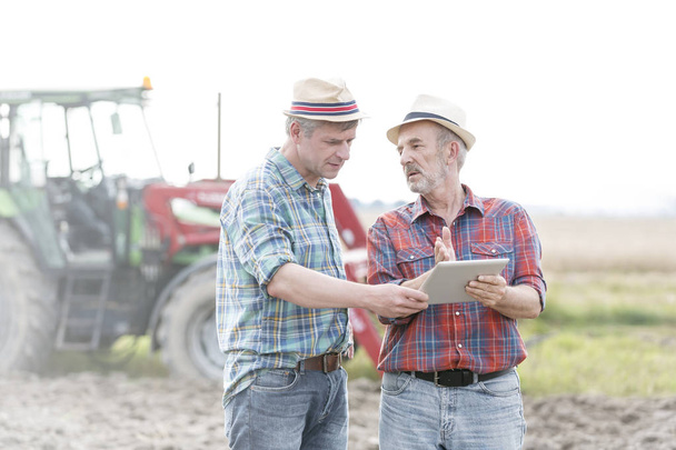 Farmers with digital tablet discussing at farm - 写真・画像
