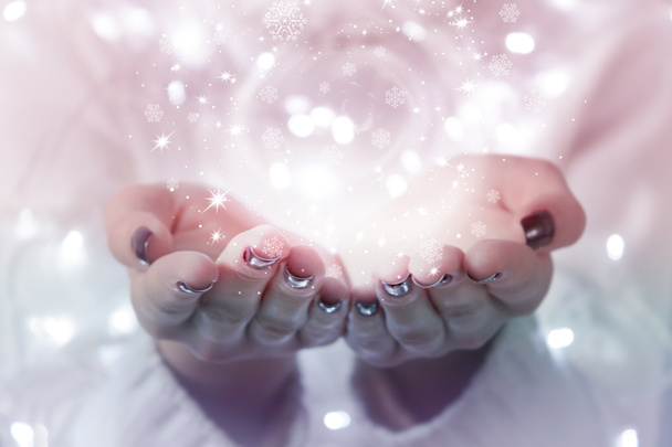 Μαγικό σωματίδια που προέρχονται από γυναικεία χέρια. Χριστουγεννιάτικο φόντο με bokeh - Φωτογραφία, εικόνα