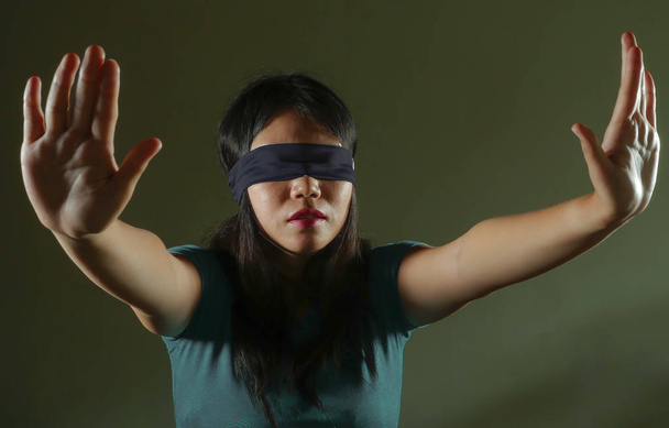 young scared and blindfolded Asian Korean teenager girl lost and confused playing dangerous internet viral challenge isolated on dark background under edgy and dramatic studio light - Fotó, kép