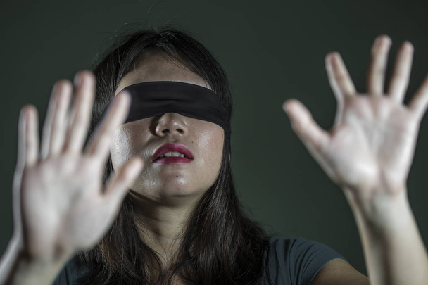 young scared and blindfolded Asian Korean teenager girl lost and confused playing dangerous internet viral challenge isolated on dark background under edgy and dramatic studio light - Fotó, kép