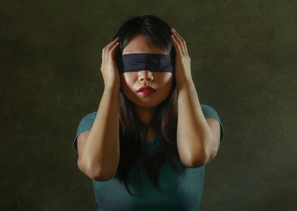 young scared and blindfolded Asian Chinese teenager girl lost and confused playing dangerous internet viral challenge isolated on dark background under edgy and dramatic studio light - Fotó, kép