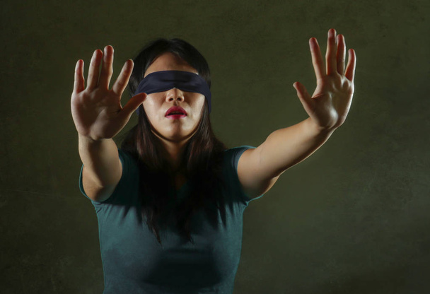 young scared and blindfolded Asian Chinese teenager girl lost and confused playing dangerous internet viral challenge isolated on dark background under edgy and dramatic studio light - Foto, Bild