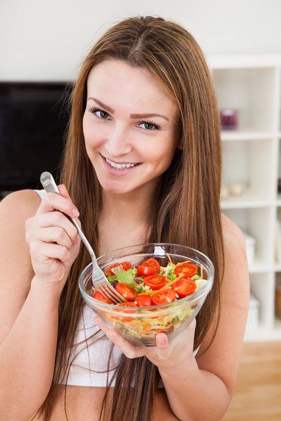 Primer plano de una atractiva mujer joven comiendo ensalada de frutas
 - Foto, imagen
